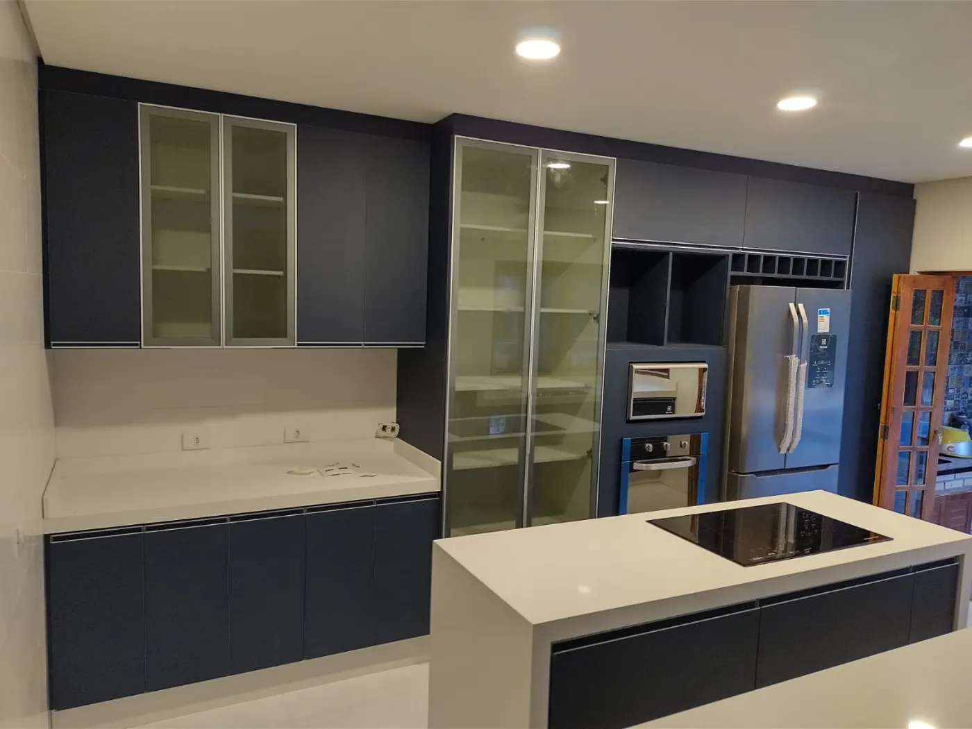 Cozinha com armários azul-escuros e ilha com cooktop em pedra branca