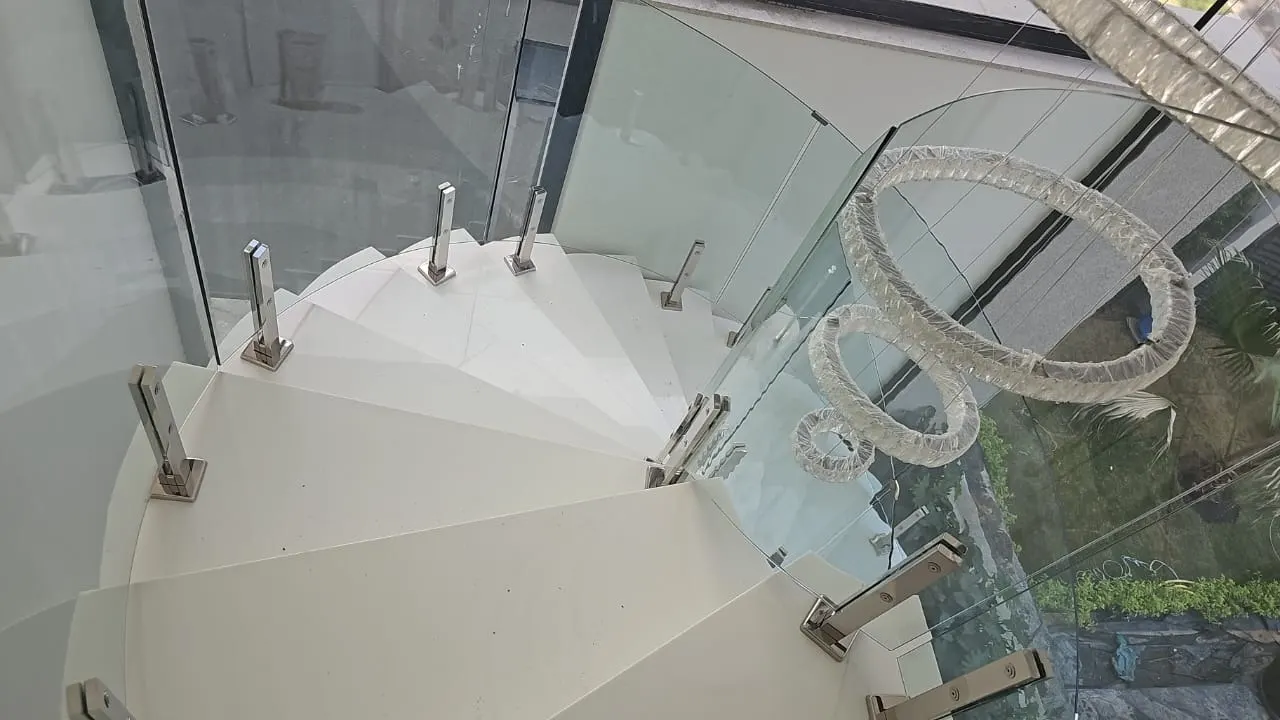 Escada em caracol com degraus de pedra clara e vidro
