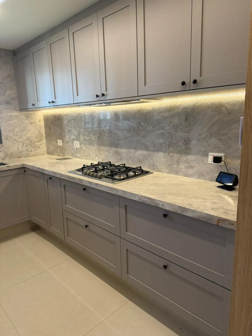 Bancada com cooktop e frontão de pedra iluminado por fita de led